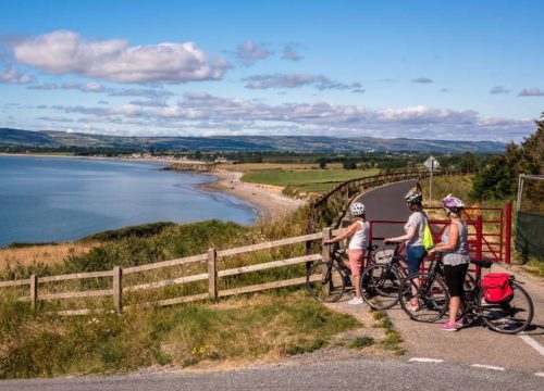 Two cyclists taking a break to enjoy the scenic view of the Copper Coast on a sunny day.