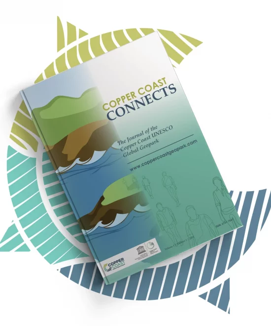 A magazine titled "Copper Coast Connects," featuring a graphic design of people and scenic views, rests on a geometric background with green and white stripes.