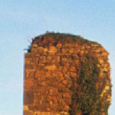 Pixelated view of the historical Dunhill Castle, a golden-hued cylindrical building, against a clear blue sky.