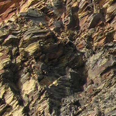 Rugged texture of a rocky surface at Kilfarrasy Strand displaying various shades of brown and hints of shimmering minerals on the beach.